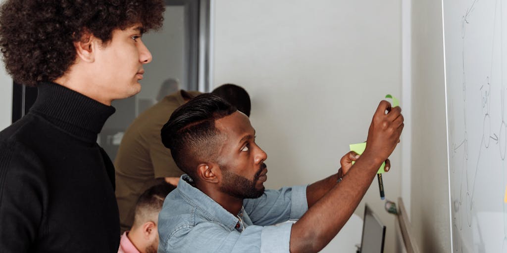 A dynamic photo of a brainstorming session in a design studio, where a diverse team is actively discussing and mapping out customer needs using sticky notes and a whiteboard. The background shows sketches and diagrams related to the Kano Model, emphasizing collaboration and the importance of understanding customer expectations in product development.