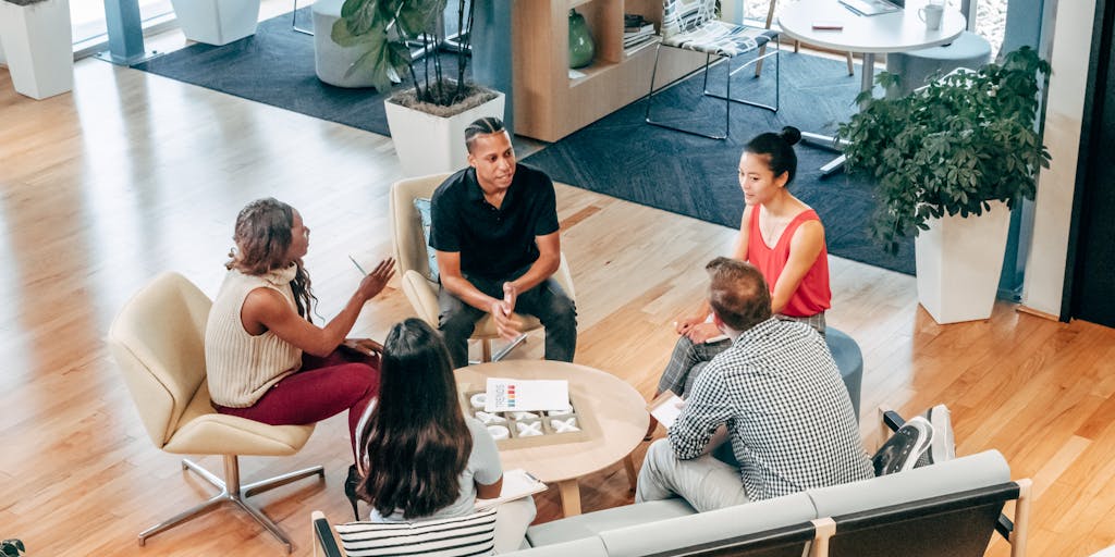 A vibrant workspace featuring a diverse group of professionals collaborating over digital marketing strategies. The scene includes laptops displaying analytics dashboards, colorful sticky notes on a whiteboard, and a large screen showing social media trends. The atmosphere is dynamic and creative, highlighting teamwork in the digital age.