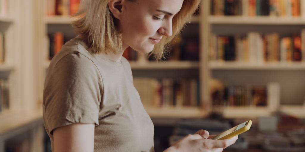 A close-up shot of a shopper using a mobile app in-store, with personalized product recommendations displayed on their screen. The background shows shelves filled with products, emphasizing the integration of digital media in the retail experience.