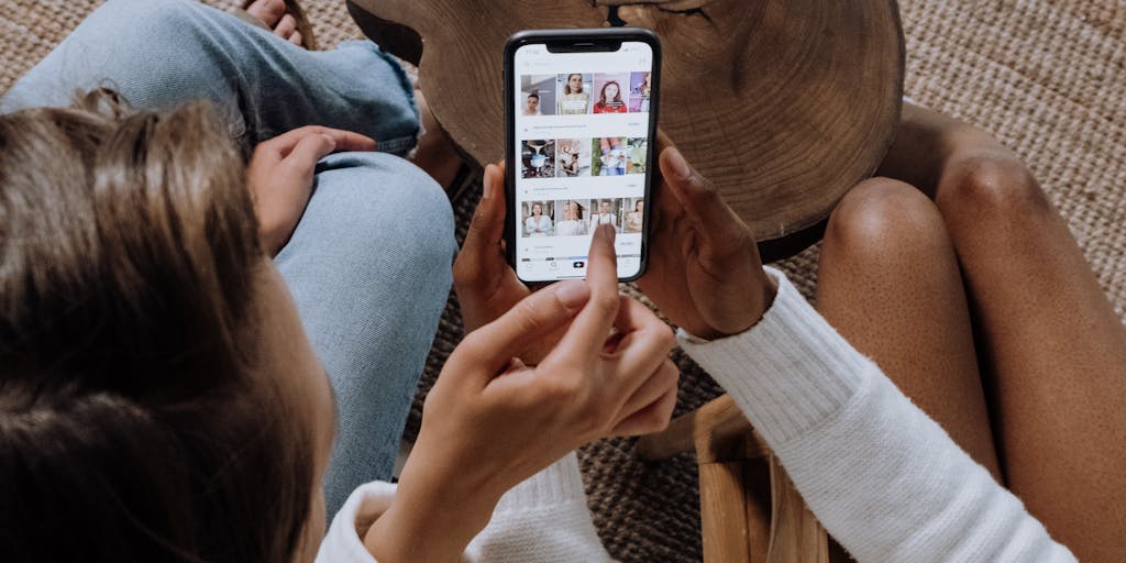 A close-up shot of a hand holding a smartphone displaying a post with a high engagement rate, surrounded by a group of friends laughing and reacting to the post. This captures the excitement and joy of sharing moments that resonate with others.