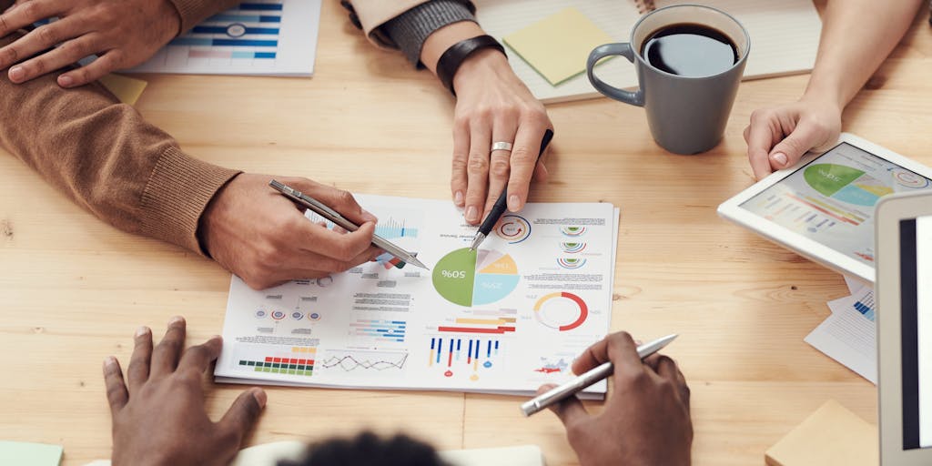 A dynamic image of a diverse group of marketers brainstorming around a table filled with charts, graphs, and Amazon product listings. Capture the energy of collaboration with sticky notes and laptops open, showcasing a real-time strategy session.