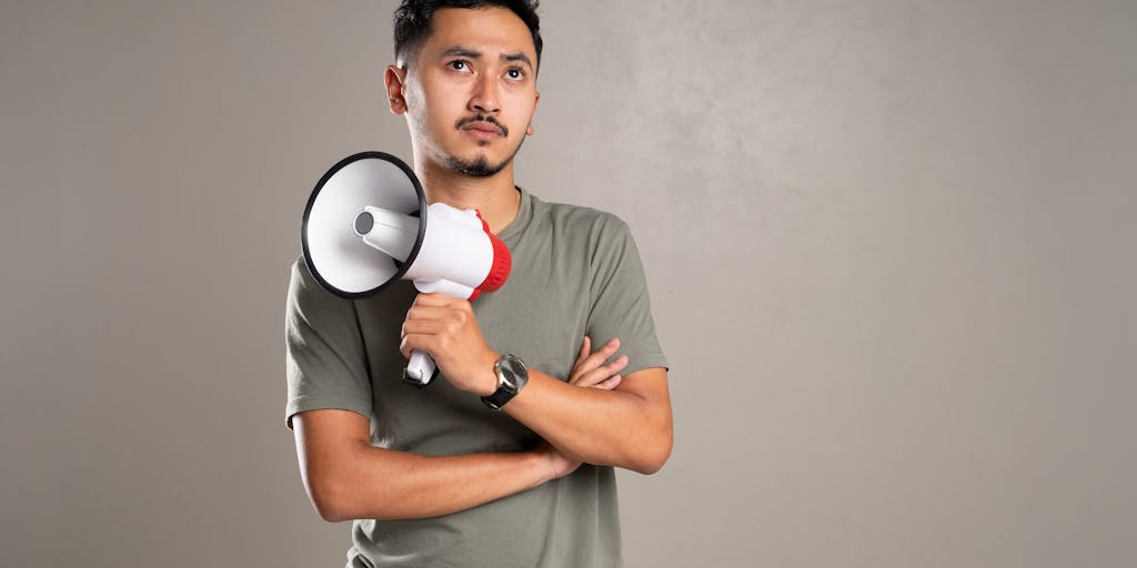 A conceptual photo of a person holding a megaphone in front of a large eBay logo, symbolizing the amplification of marketing messages. The background should be a bustling marketplace, representing the vibrant community of buyers and sellers on eBay, with colorful banners promoting various products.