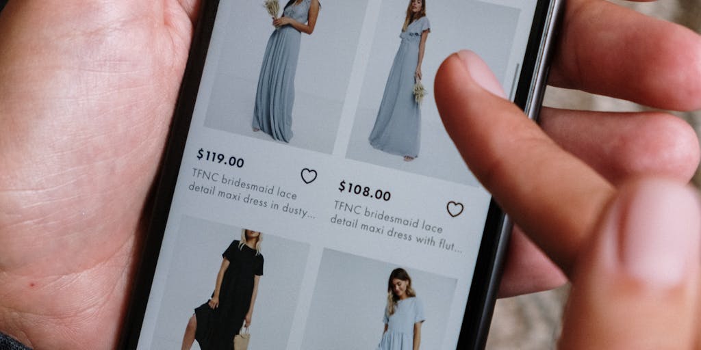 A close-up of a smartphone displaying a Shopify store on the screen, with a hand holding it and a shopping bag in the background. This image should convey the mobile shopping experience and the importance of mobile marketing strategies in e-commerce.