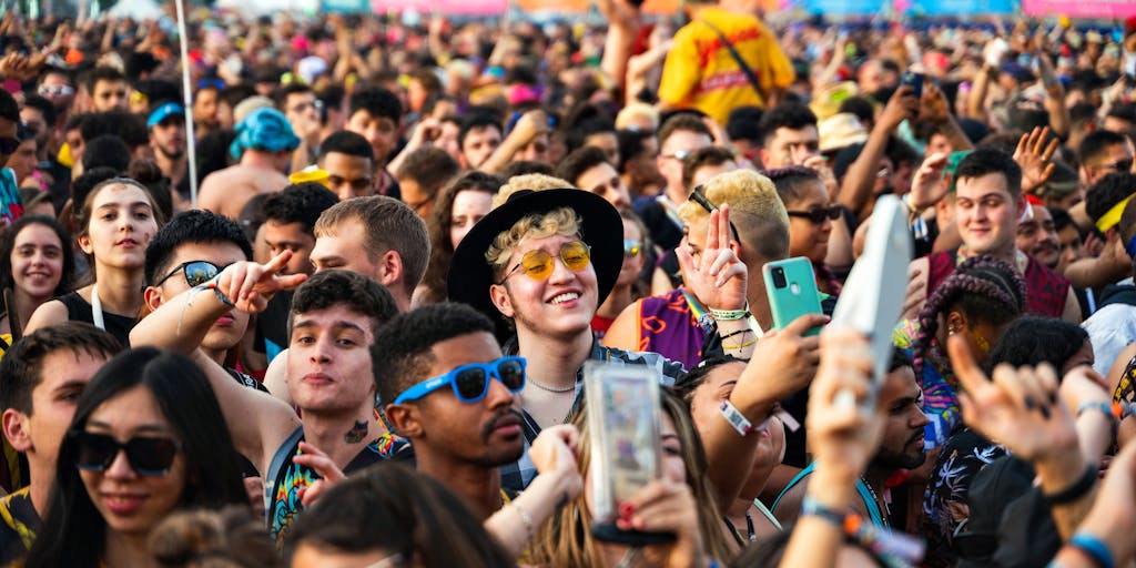 A vibrant outdoor scene featuring a diverse group of people wearing stylish eyewear from Lenskart, engaging in various activities like reading, playing sports, and socializing. The background showcases a colorful mural that represents the brand's youthful and trendy image, emphasizing inclusivity and lifestyle.