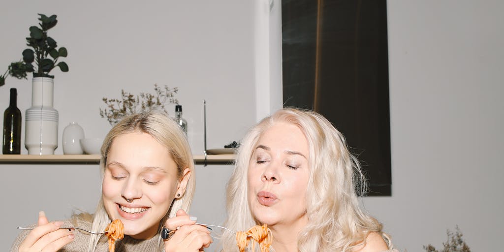 A close-up of a family enjoying a HelloFresh meal at the dinner table, with smiles and animated conversation. The focus is on the food, with a blurred background of family members, showcasing the connection and joy that comes from sharing a home-cooked meal together.