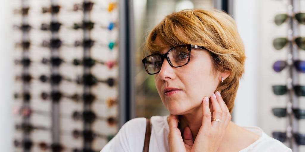 A close-up shot of a customer trying on Warby Parker glasses in a stylish boutique setting, with a mirror reflecting their joyful expression. The image captures the personal connection and experience of trying on eyewear, emphasizing the brand's customer-centric approach.