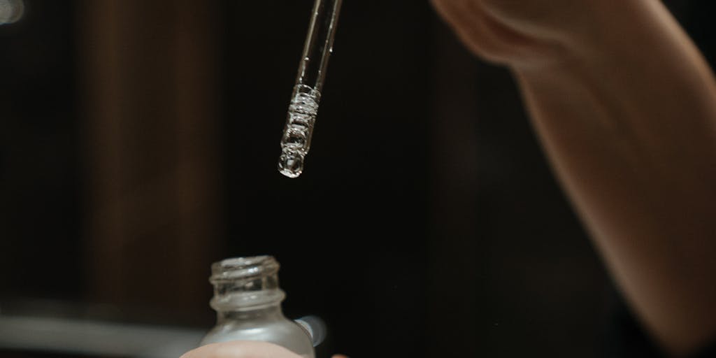 A close-up shot of a Glossier product being applied to the skin, with a focus on the texture and glow. The background should be blurred to emphasize the product, and the lighting should create a soft, inviting atmosphere, reflecting the brand's emphasis on skincare and natural beauty.