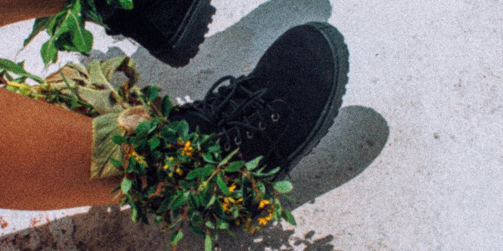 A close-up shot of Allbirds shoes placed on a natural surface, like grass or a wooden table, surrounded by elements that represent sustainability, such as recycled materials, plant-based fabrics, and eco-friendly packaging. This image highlights the brand's focus on environmentally conscious production.