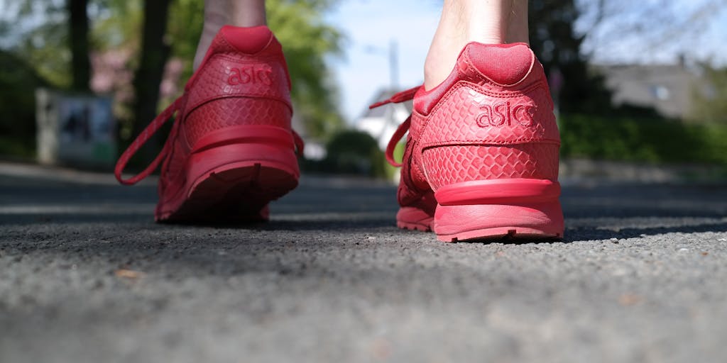 A dynamic action shot of a person running or walking in an urban environment, wearing Allbirds shoes, with a backdrop of green spaces integrated into the city. This image captures the essence of urban sustainability and the brand's appeal to active, environmentally aware consumers.