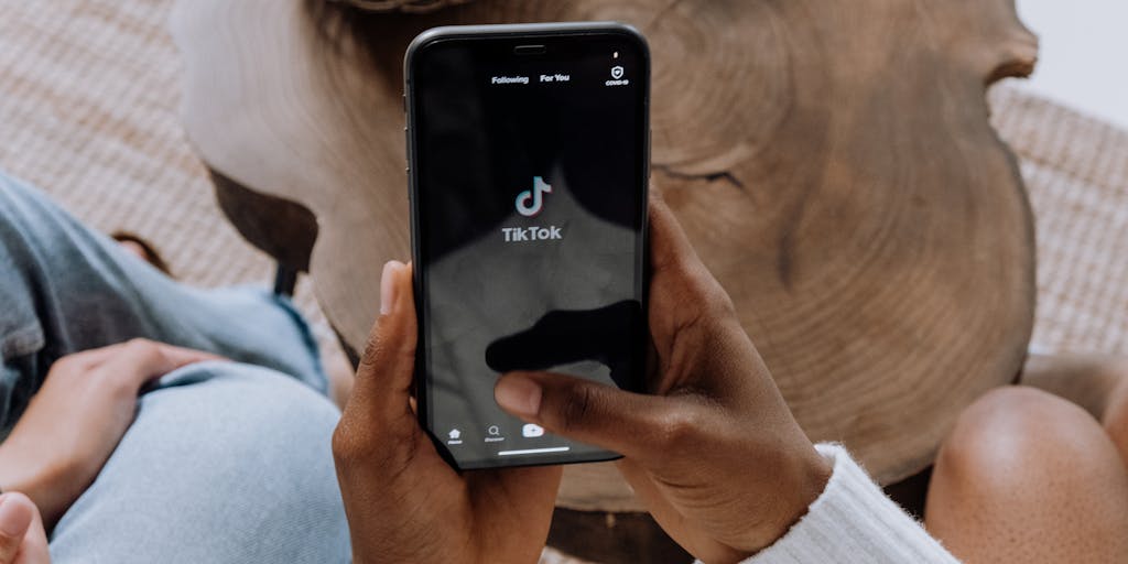 A close-up shot of a smartphone displaying social media analytics, with a hand holding the phone and a notepad with marketing notes in the background. The focus should be on the screen, highlighting key metrics like engagement rates and follower growth.