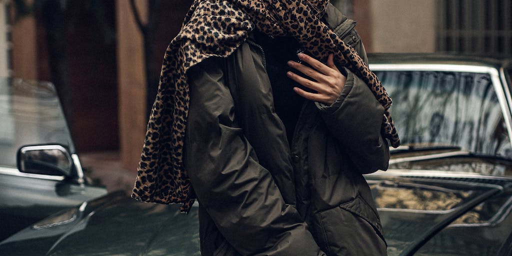 A dynamic photo of a young person wearing a stylish outfit sourced from Depop, standing in an urban setting. The individual is posing confidently, with a Depop shopping bag in hand, highlighting the thrill of second-hand shopping and the unique style that can be found on the platform.