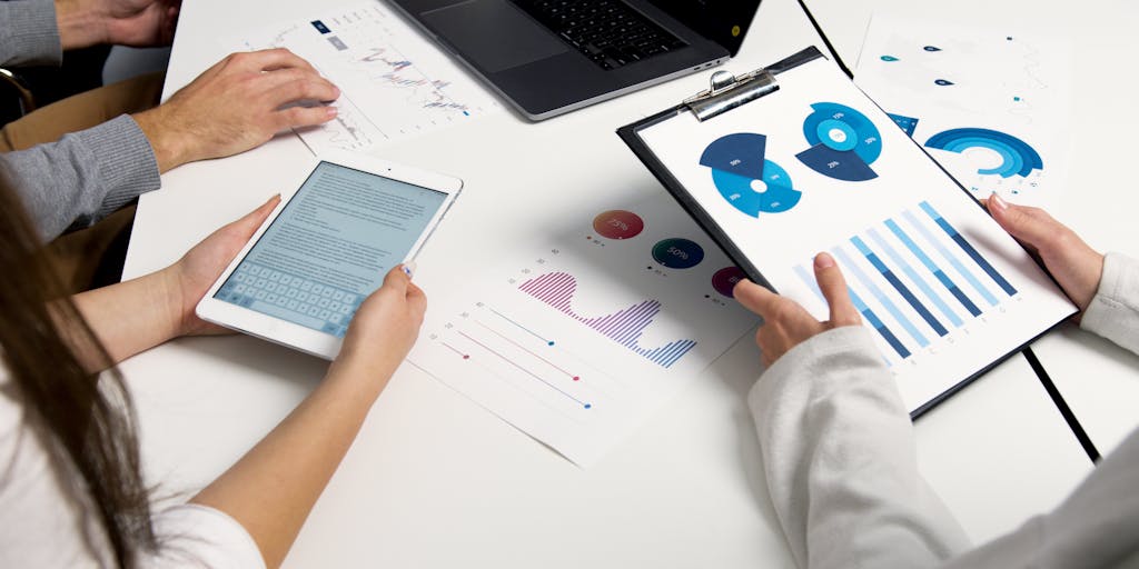 An overhead shot of a laptop on a desk surrounded by Adobe marketing materials, such as brochures, infographics, and a coffee cup. The laptop screen shows a colorful dashboard of Adobe Analytics, emphasizing data-driven decision-making.