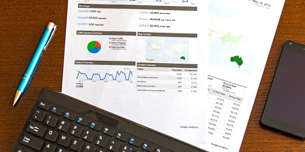 An overhead shot of a laptop displaying SAP marketing analytics dashboards, surrounded by coffee cups, notepads, and digital devices. The scene conveys a sense of focus and data-driven decision-making, highlighting the analytical aspect of SAP marketing strategies.