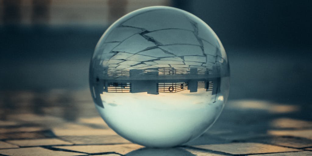 An artistic representation of a crystal ball with various marketing icons (like social media, email, and analytics) floating around it. The background is a blurred cityscape, symbolizing the connection between foresight in marketing and the urban market landscape.