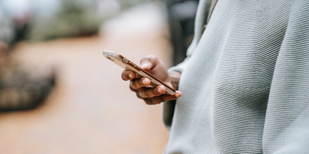 A close-up of a hand holding a smartphone displaying the ServiceNow app, with a blurred background of a busy city street. This image represents the mobile-first approach in marketing strategies, highlighting the importance of accessibility and user engagement.