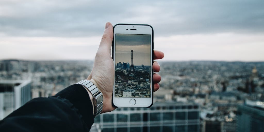 A close-up of a hand holding a smartphone displaying the Dropbox app, with a blurred background of a bustling cityscape. This photo should symbolize the on-the-go accessibility of Dropbox, emphasizing how users can manage their files anytime, anywhere.