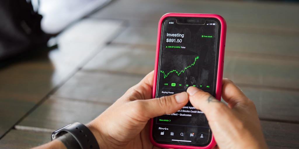 A close-up shot of a smartphone displaying the Datadog mobile app, surrounded by analytics graphs and charts on a desk. The image conveys the idea of data accessibility and real-time monitoring, essential elements of Datadog's marketing strategy.