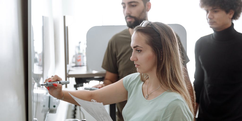 A vibrant brainstorming session in a modern office setting, featuring a diverse team of professionals gathered around a whiteboard filled with colorful sticky notes and diagrams. The atmosphere is energetic, showcasing collaboration and creativity in developing a marketing strategy for SurveyMonkey.