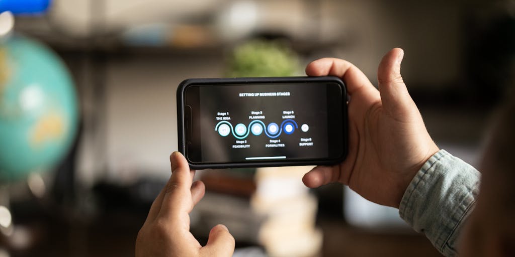 A close-up of a hand holding a smartphone displaying the Xero app, with a notepad and pen in the background. The notepad has scribbled marketing ideas and strategies, symbolizing the integration of technology and traditional planning in Xero's marketing approach.