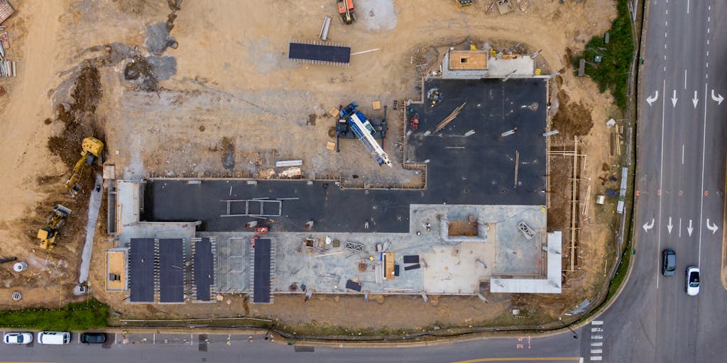 An aerial view of a construction site with workers and machinery, overlaid with digital graphics representing data analytics and marketing metrics. This image visually connects Procore's marketing strategy to the construction industry, highlighting the integration of technology and data in their approach.