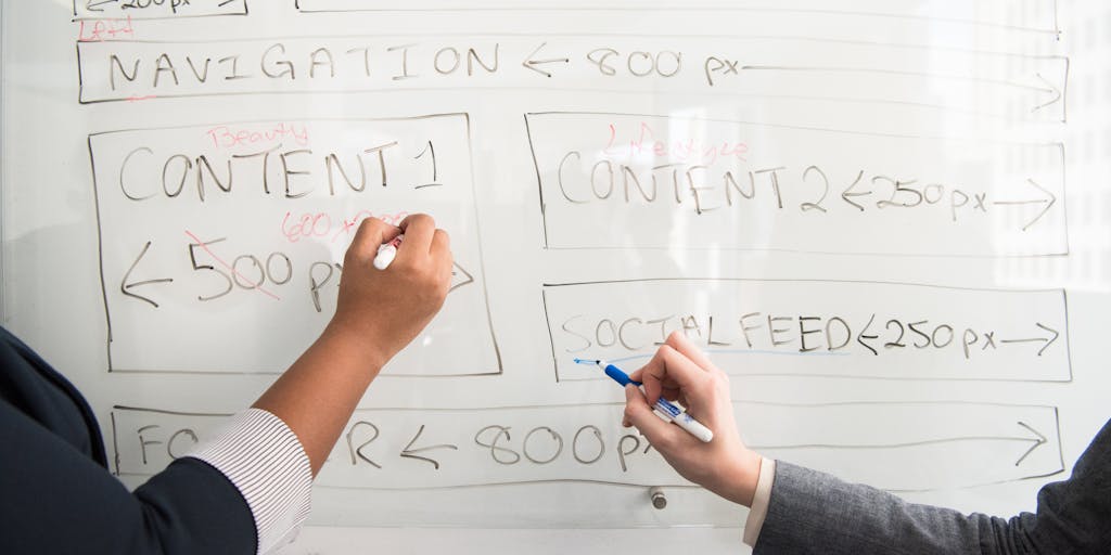 A close-up of a hand writing on a notepad with a pen, with a blurred background of a Pipedrive marketing presentation on a screen. The focus on the handwritten notes emphasizes the importance of planning and strategy in marketing, while the digital aspect represents modern marketing tools.