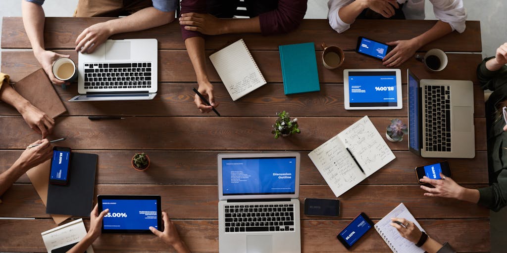 An overhead shot of a team brainstorming around a square table, with sticky notes and digital devices scattered across the surface. The focus is on the collaborative aspect of developing a marketing strategy, showcasing diverse ideas and perspectives in a square format.