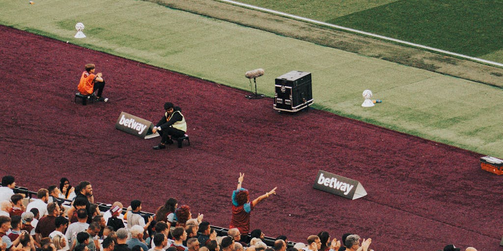 A dynamic photo of a Chelsea FC digital marketing campaign in action, featuring a large screen displaying social media interactions and fan-generated content. The image includes fans engaging with the club's online platforms, illustrating the importance of digital marketing in connecting with supporters.