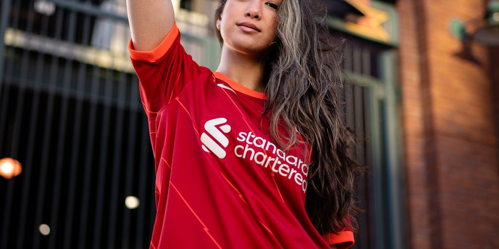 A close-up shot of a young fan holding a signed Everton FC jersey, with a backdrop of the stadium. The fan's expression of joy and pride highlights the emotional connection between the club and its supporters, emphasizing the importance of fan engagement in the marketing strategy.