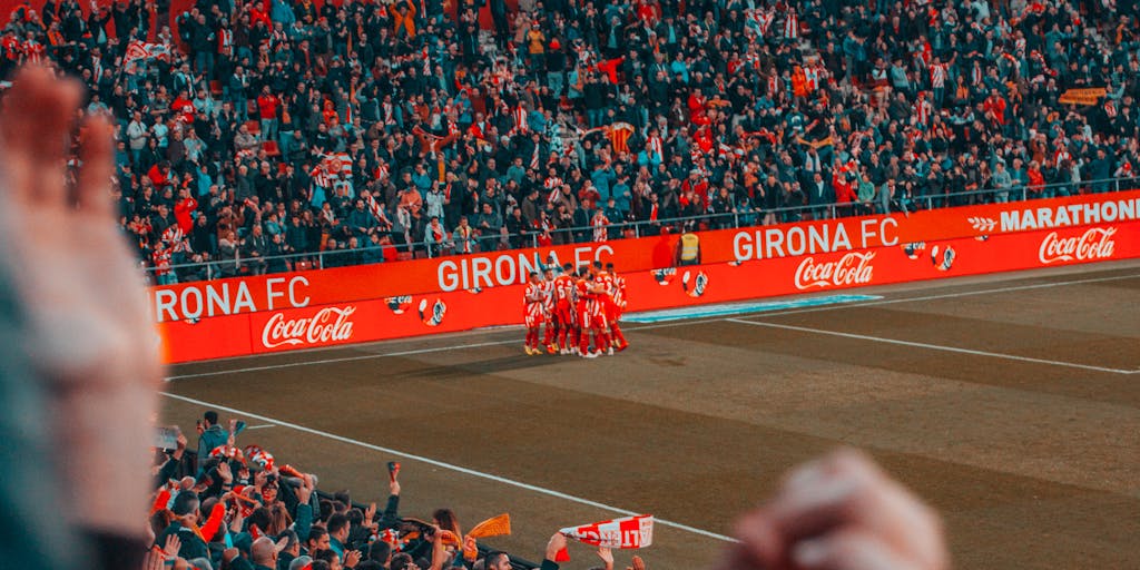 A dynamic action shot of Everton FC players celebrating a goal, with fans in the background cheering wildly. This image captures the excitement of match day and the emotional investment of the supporters, which is a key element in the club's marketing narrative.