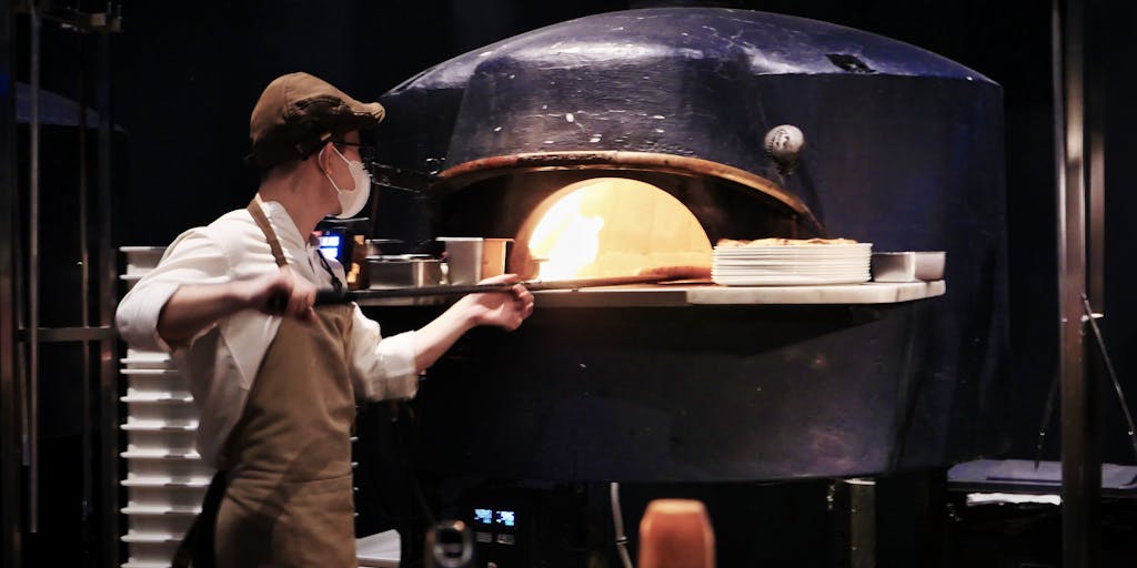 A close-up shot of a local pizza chef preparing a traditional Neapolitan pizza, with ingredients artfully arranged around him. The photo emphasizes the importance of authentic local cuisine in marketing strategies aimed at attracting food tourism.