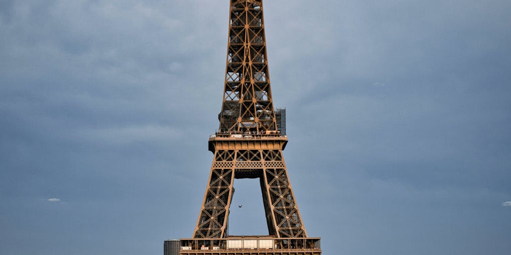 A vibrant street scene in Paris featuring a group of diverse fans wearing Paris Saint-Germain jerseys, holding scarves and flags, with the Eiffel Tower in the background. The photo captures the excitement of match day, showcasing the club's global fanbase and its connection to the city.