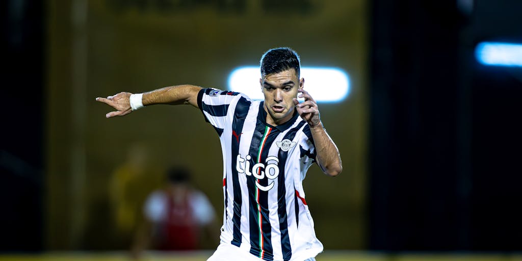 A dynamic action shot of a PSG player in mid-kick, with a blurred background of a packed stadium filled with cheering fans. The image emphasizes the energy of a live match and the club's commitment to thrilling performances, reflecting their marketing focus on sports excellence.