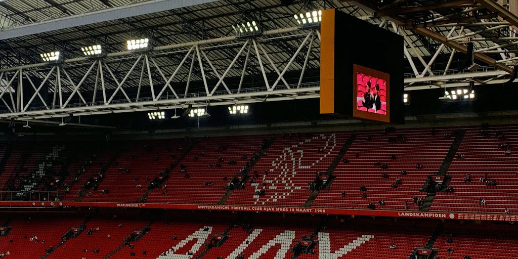 A vibrant collage showcasing Ajax Amsterdam's iconic red and white colors, featuring fans in the stadium, merchandise, and social media engagement. The image should capture the essence of community and passion surrounding the club, with a focus on how marketing strategies connect fans to the team.