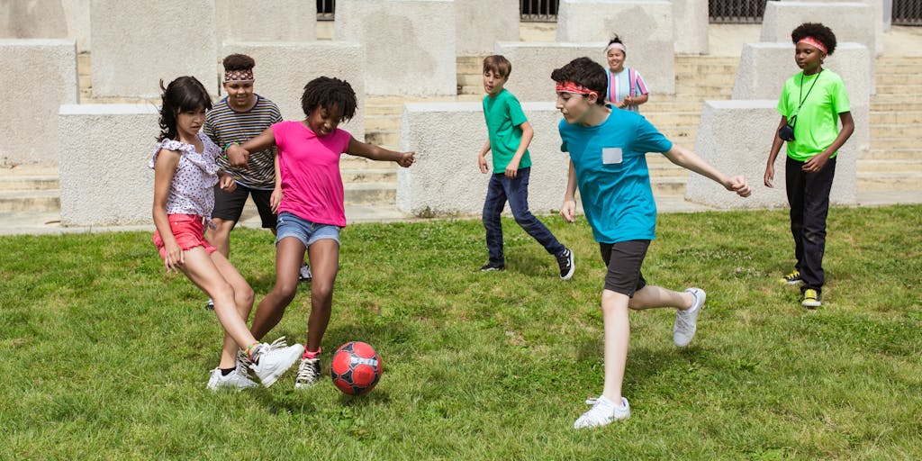 A dynamic image of a Benfica player engaging with young fans during a community event, such as a soccer clinic. The player is demonstrating a skill while the kids are eagerly watching and participating, showcasing Benfica's commitment to youth development and local outreach.