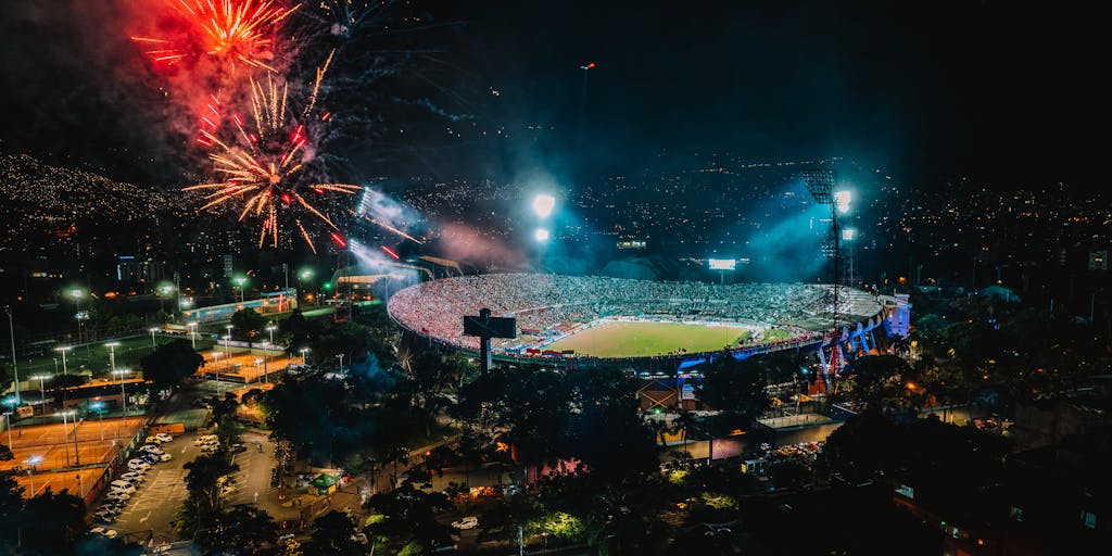 An artistic shot of the Estádio do Dragão illuminated at night, with a focus on the stadium's unique architecture. The image should include a few fans entering the stadium, showcasing the excitement and anticipation before a match, symbolizing the club's strong brand presence.