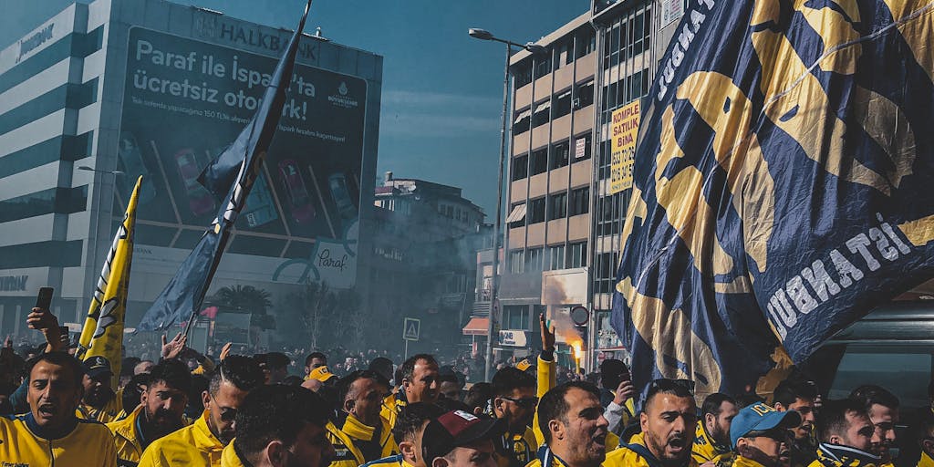 A vibrant photo capturing a diverse group of Fenerbahçe fans wearing the team's colors, gathered in a lively urban setting, showcasing their passion and unity. The background features iconic landmarks of Istanbul, symbolizing the club's deep roots in the city. This image represents the community aspect of Fenerbahçe's marketing strategy.