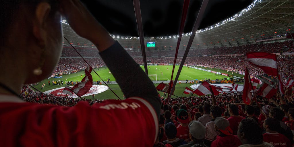 An overhead shot of a packed stadium during a Flamengo match, with fans creating a colorful mosaic of red and black in the stands. This image highlights the emotional connection and engagement that Flamengo's marketing strategy fosters among its supporters.