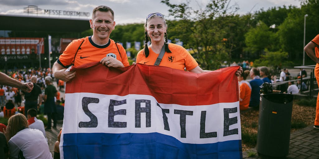 A vibrant photo capturing a diverse group of Seattle Sounders fans wearing team jerseys, holding scarves, and cheering in a packed stadium. The image should convey the energy and passion of the fanbase, with colorful banners and flags in the background, showcasing the community aspect of the Sounders' marketing strategy.