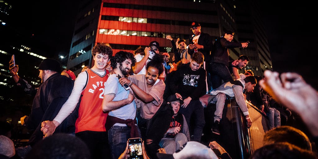 A vibrant street scene capturing a diverse group of fans wearing Toronto FC jerseys, holding scarves, and cheering in front of a popular Toronto landmark, such as the CN Tower. The photo should convey the excitement and community spirit surrounding the team, with a focus on inclusivity and passion for soccer.