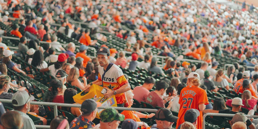 An overhead shot of a packed NRG Stadium during a game, with fans waving Texans flags and wearing team colors. The image highlights the electric atmosphere of a live game, showcasing the team's branding and the emotional connection fans have with the Texans.