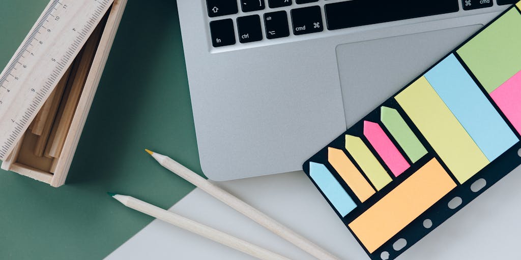 A flat lay of a laptop displaying the Systeme.io dashboard, surrounded by colorful stationery, a cup of coffee, and a notepad with handwritten notes about online marketing strategies. The scene should convey a productive workspace atmosphere.