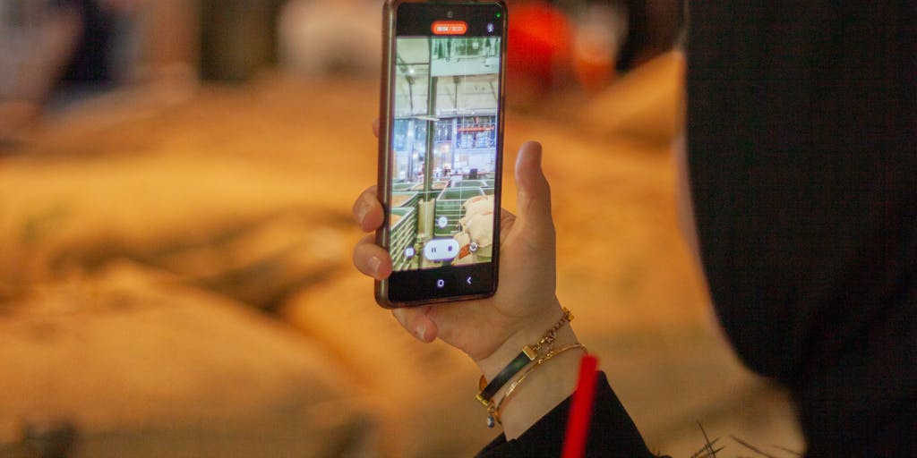 A close-up shot of a hand holding a smartphone displaying the Systeme.io mobile app, with a blurred background of a coffee shop. This image should evoke a sense of convenience and modernity in managing online business tasks on the go.
