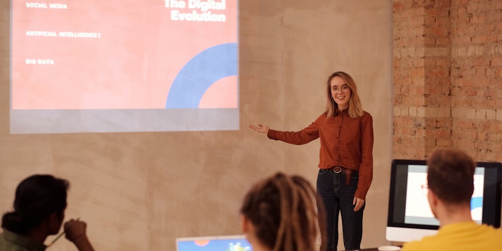 A dynamic image of a business professional pointing at a large screen displaying Salesloft pricing options during a presentation. The audience is engaged, with expressions of interest and curiosity, highlighting the importance of pricing in sales.