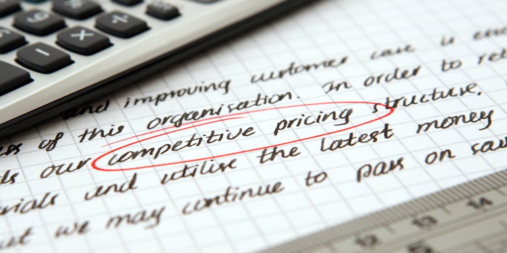 A creative flat lay of a calculator, sticky notes with pricing ideas, and a pen, all arranged on a wooden table. The sticky notes have handwritten pricing strategies and outreach voice service names, giving a personal touch to the pricing concept.