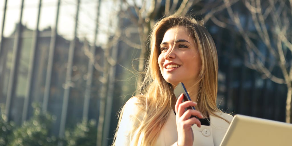 A close-up shot of a hand holding a smartphone displaying the Expandi Pricing page, with a blurred background of a bustling cityscape. The focus on the phone highlights the digital aspect of pricing strategies in a modern business environment.