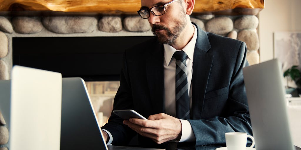 An overhead view of a desk with a laptop open to the Sales Loft pricing page, alongside a cup of coffee, a notepad filled with sales notes, and a smartphone displaying a sales app. The composition should evoke a sense of productivity and focus on pricing strategies.