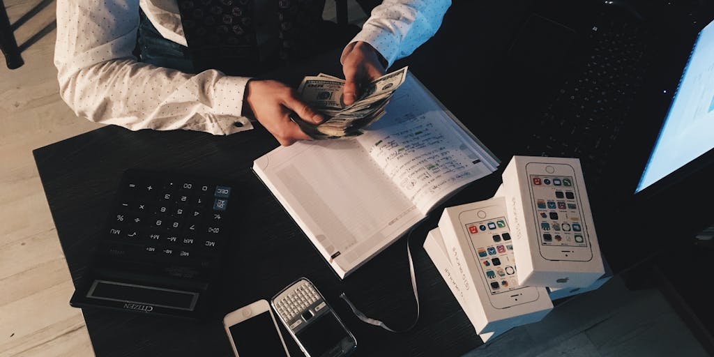 An overhead view of a desk cluttered with various pricing documents, a laptop with an email draft open, and colorful sticky notes with pricing ideas. The scene is vibrant and creative, showcasing the brainstorming process for pricing strategies.