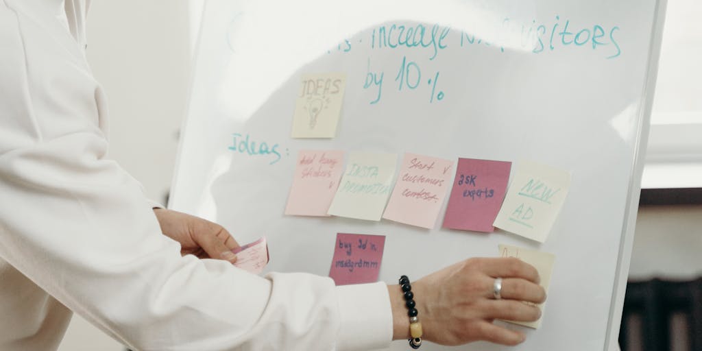 A dynamic photo of a group of diverse professionals in a brainstorming session, with a whiteboard in the background displaying Waalaxy's pricing options. The group should be animatedly discussing and pointing at the board, showcasing collaboration and the importance of choosing the right pricing plan for their needs.