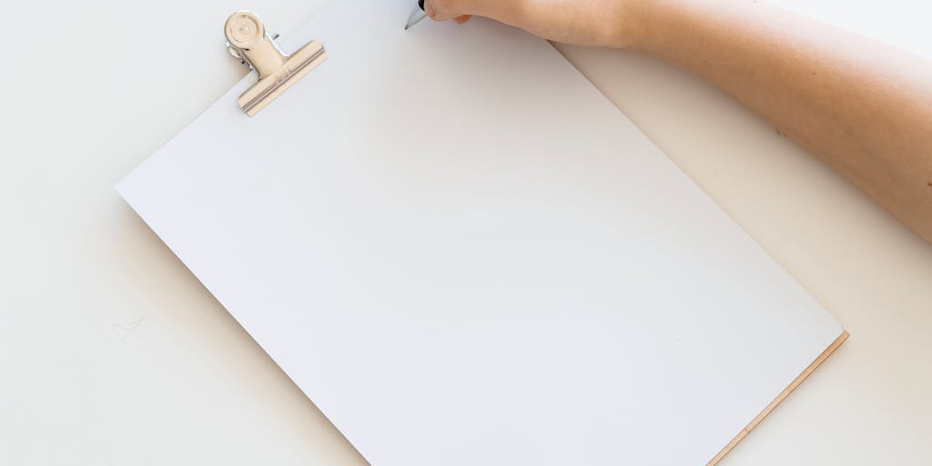 A conceptual image of a person holding a magnifying glass over a printed pricing sheet for Yet Another Mail Merge, with a blurred background of a busy office environment. This symbolizes the importance of scrutinizing pricing options.