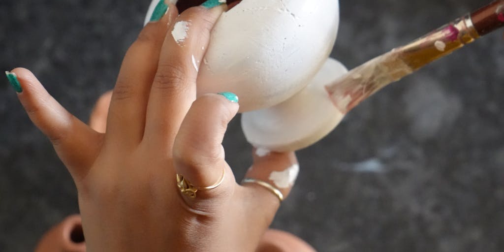 A close-up shot of a hand sculpting a clay model that represents different pricing tiers, with each tier symbolized by a unique shape or color. The background is softly blurred to emphasize the clay work, and a price tag is subtly placed next to each shape.